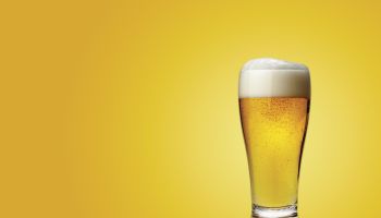 Glass of beer on colored background