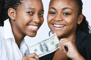 Two beautiful, smiling young women with $100 bill