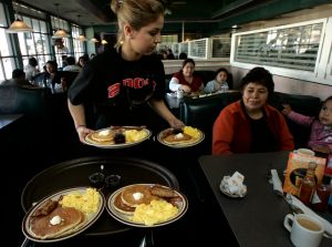 Gaby Estrella (Cq), serves Grand Slam breakfast at Denny's Restaurant in Santa Ana on the morning o