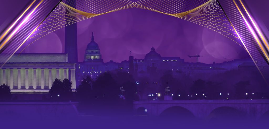 A nighttime cityscape with a purple-hued sky, illuminated domes and spires, and a suspension bridge in the foreground.